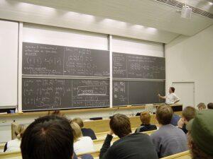 Professor writes equations on a chalkboard.